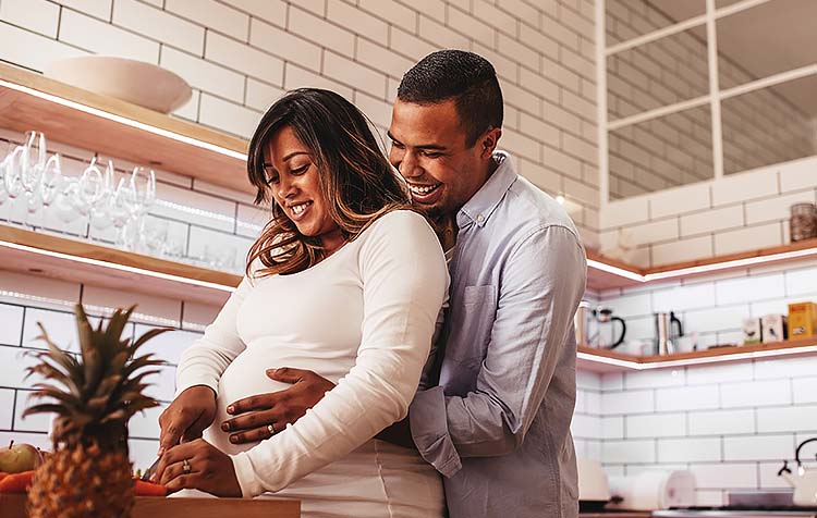 Pregnant woman and man cooking in kitchen