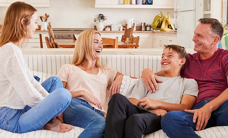 Two teenagers with parents on sofa at home