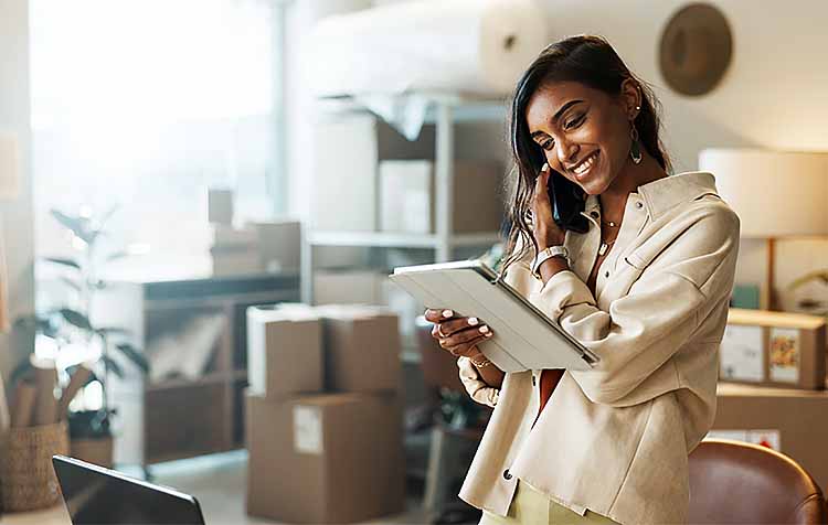 Business owner looking happily at an iPad standing in her business office