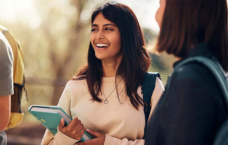 Student with book laughing next to friends