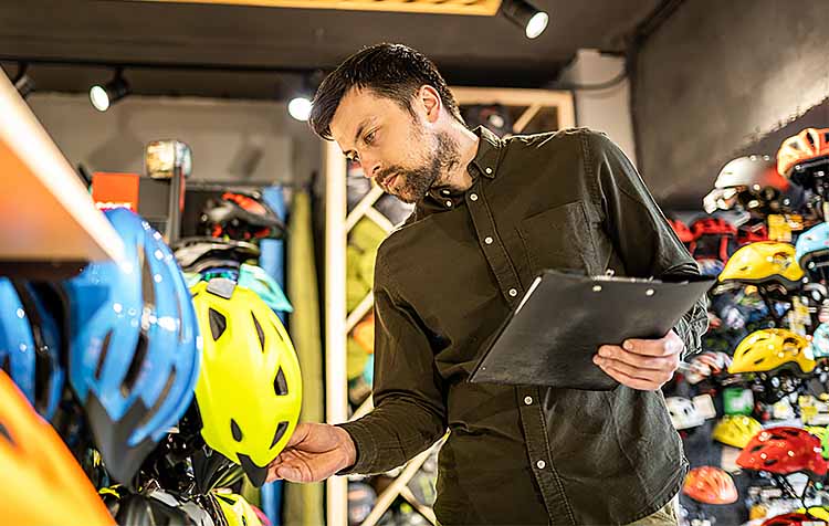 Bike shop owner takes inventory of helmets.